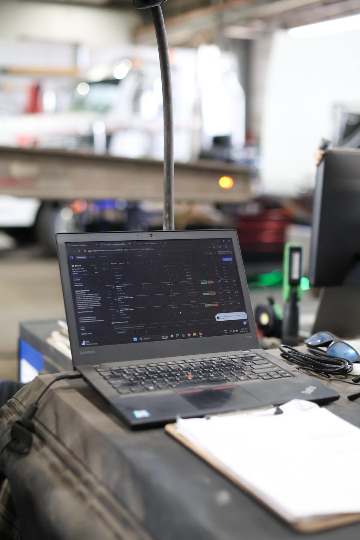 Shop management software open on a laptop in a service bay
